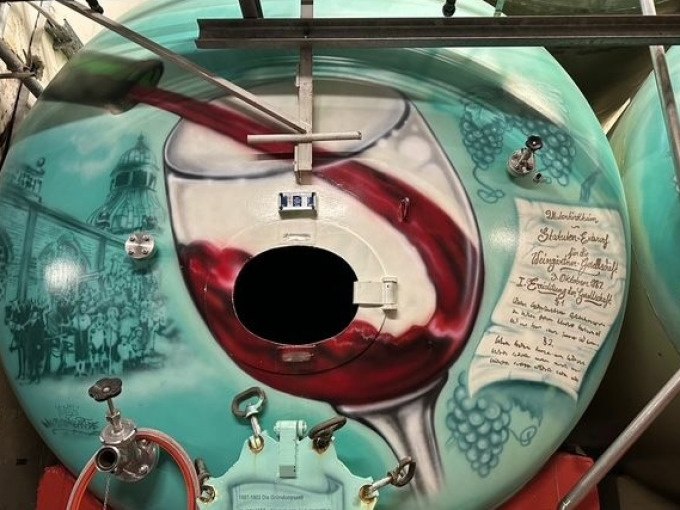 Ein Weintank mit kunstvoller Bemalung zeigt ein Weinglas und Trauben. Eine Inschrift und historische Abbildungen sind ebenfalls zu sehen., © Weingenuss Stuttgart Ein Weintank mit kunstvoller Bemalung zeigt ein Weinglas und Trauben. Eine Inschrift und historische Abbildungen sind ebenfalls zu sehen., © Weingenuss Stuttgart