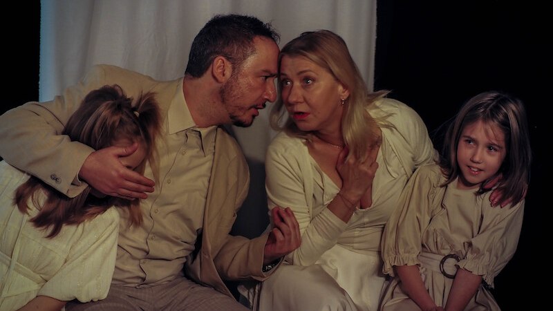Seven people in white clothing pose in front of a neutral background. One person is holding a hat. They all look in different directions., © Theater Atelier Seven people in white clothing pose in front of a neutral background. One person is holding a hat. They all look in different directions., © Theater Atelier
