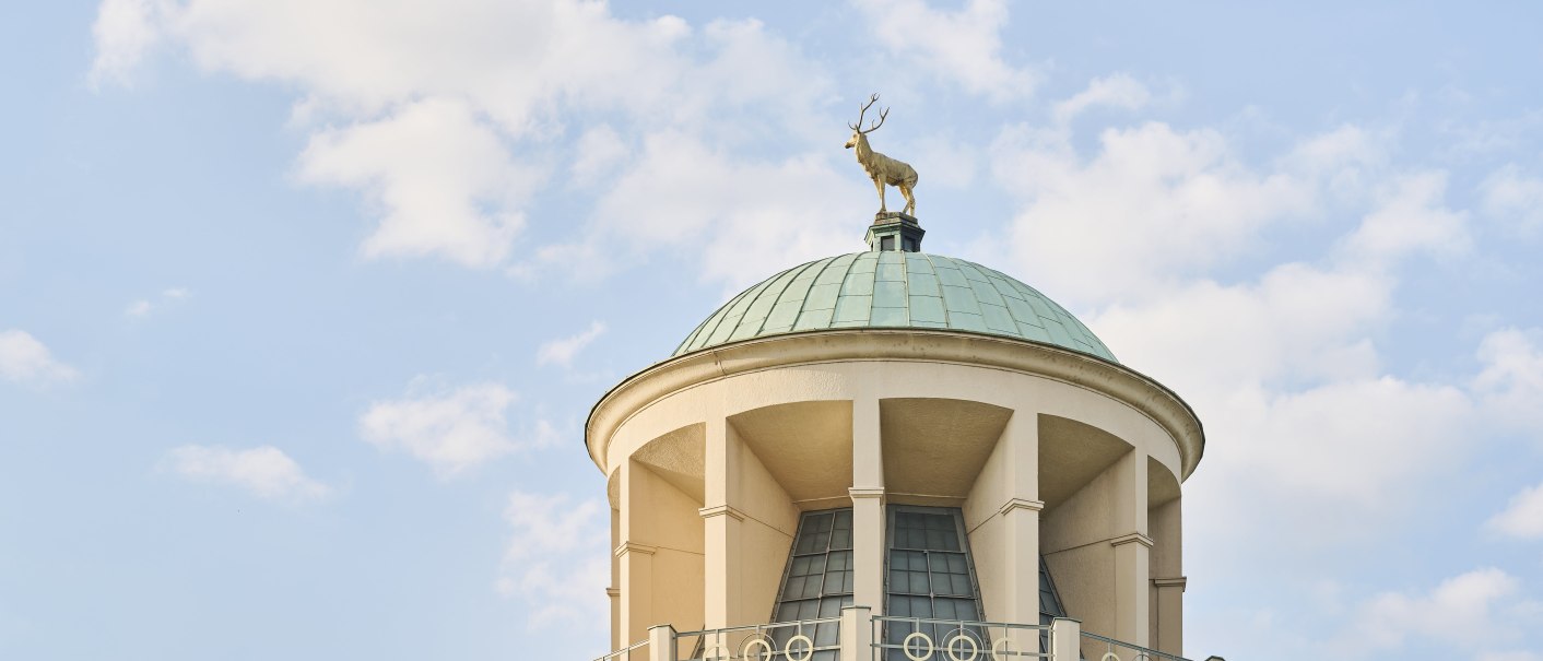 Dome of a building with a deer statue on the roof. The sky is blue with a few clouds., &copy; Simon Sommer