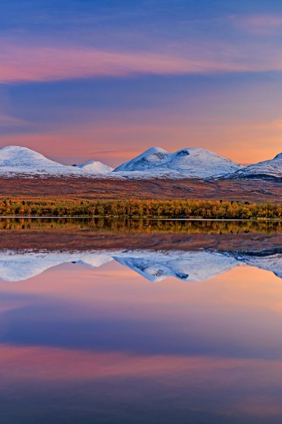 Snow-capped mountains are reflected in a calm lake. The sky is colored in soft shades of pink and blue, creating a peaceful atmosphere., &copy; Theaterhaus Stuttgart e.V.