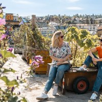 Zwei Frauen sitzen in einem urbanen Dachgarten mit Pflanzen und genießen den Ausblick auf die Stadt im Hintergrund., © © Stuttgart-Marketing GmbH, Sarah Schmid