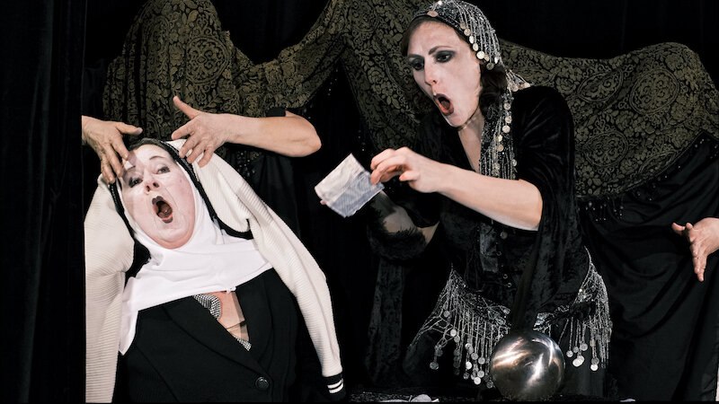 Zwei Personen in schwarzer Kleidung mit dramatischen Gesichtsausdrücken. Eine hält ein Papier, die andere trägt ein Kopftuch. Hintergrund mit schwarzem Stoff., © FITZ Das Theater animierter Formen