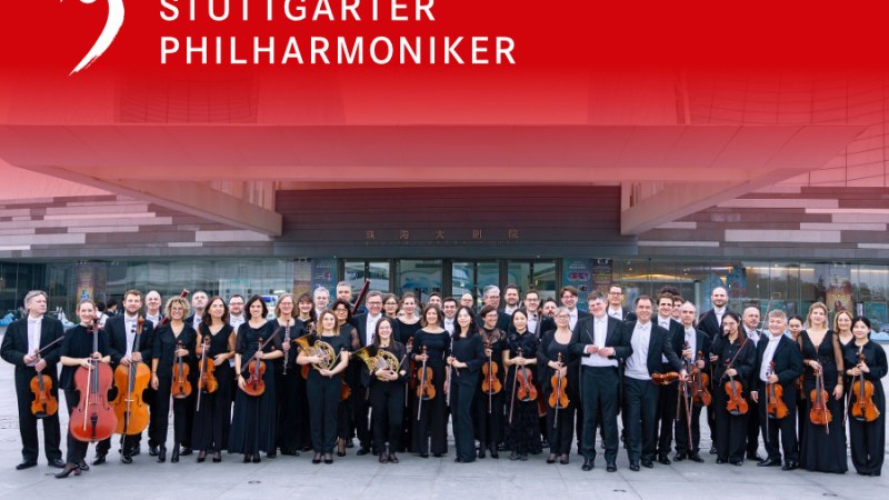Die Stuttgarter Philharmoniker posieren mit Instrumenten vor einem modernen Gebäude. Oben ist ein roter Banner mit ihrem Namen., © Juan Carlos Rivas Perretta, Stuttgarter Philharmoniker