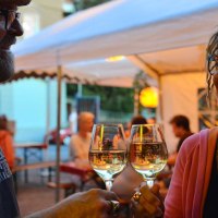 Two smiling people clink glasses of wine under a tent at a summer event., &copy; Weingut Ruoff