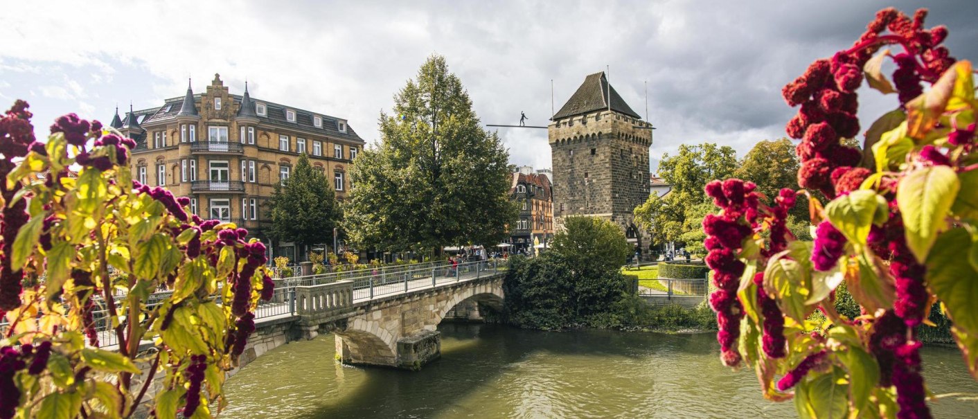 The Schelztorturm in Esslingen, surrounded by historic buildings and a bridge over a river. Colorful flowers can be seen in the foreground., © SMG Stuttgart Marketing GmbH - Sarah Schmid The Schelztorturm in Esslingen, surrounded by historic buildings and a bridge over a river. Colorful flowers can be seen in the foreground., © SMG Stuttgart Marketing GmbH - Sarah Schmid