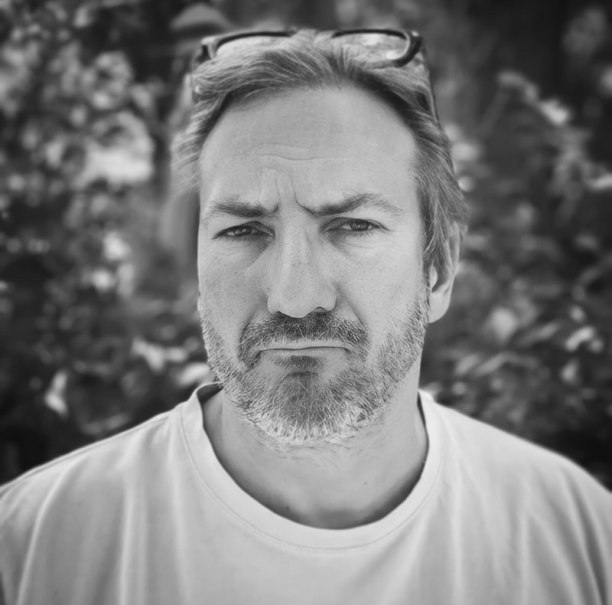 Schwarz-weiß Porträt eines Mannes mit ernstem Gesichtsausdruck und Brille auf dem Kopf, vor einem unscharfen Hintergrund., © Renitenztheater Stuttgart e.V.