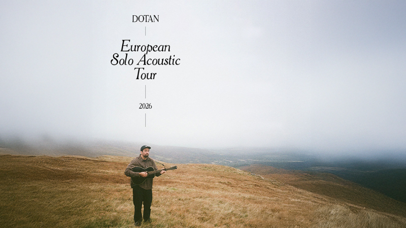 Ein Musiker steht mit einer Gitarre auf einem nebligen H&uuml;gel. Text: Dotan - European Solo Acoustic Tour 2026., &copy; links im Bild
